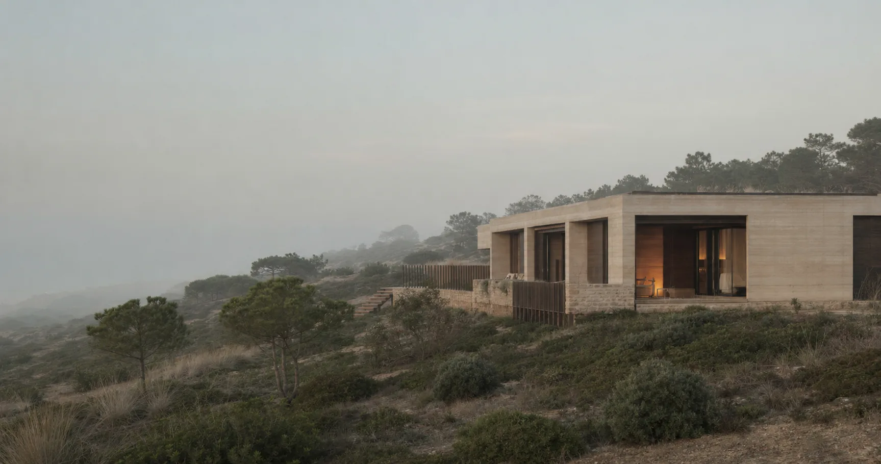 A casa principal de Bruma Rasa numa encosta de pinheiro manso, ao amanhecer, com bruma rasa sobre o vale.